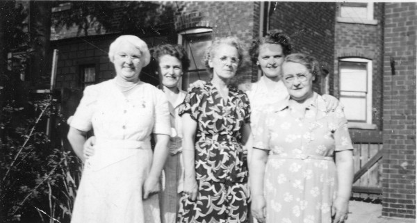 group of five women standing in garden