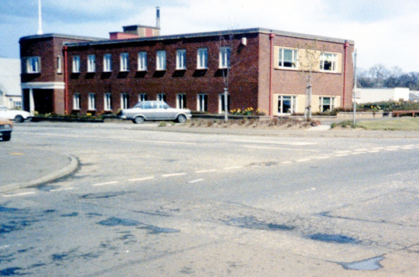 photograph of two storey brick-built building with central doorway and angled wings