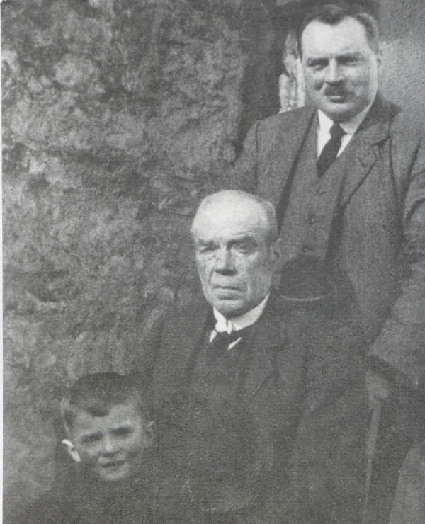 child on lap of sitting old man, standing man behind